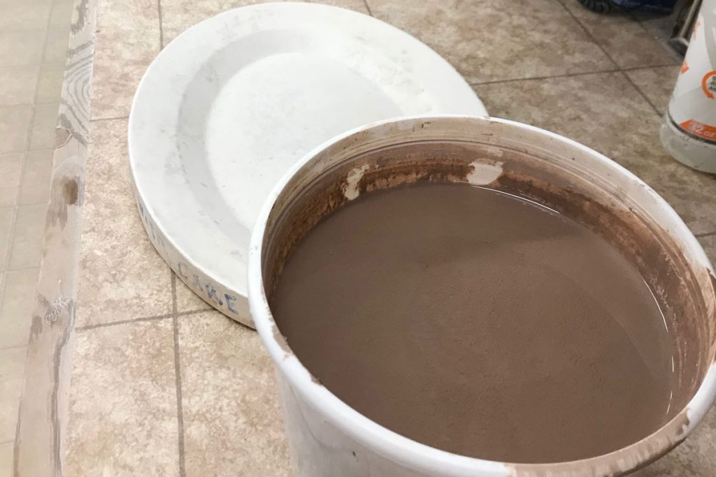 bucket of reclaim clay sludge next to plaster form