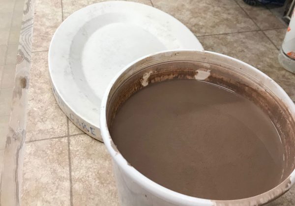 bucket of reclaim clay sludge next to plaster form